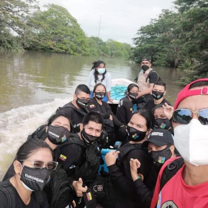 EEC team members wearing protective masks travel together in a boat on a river.