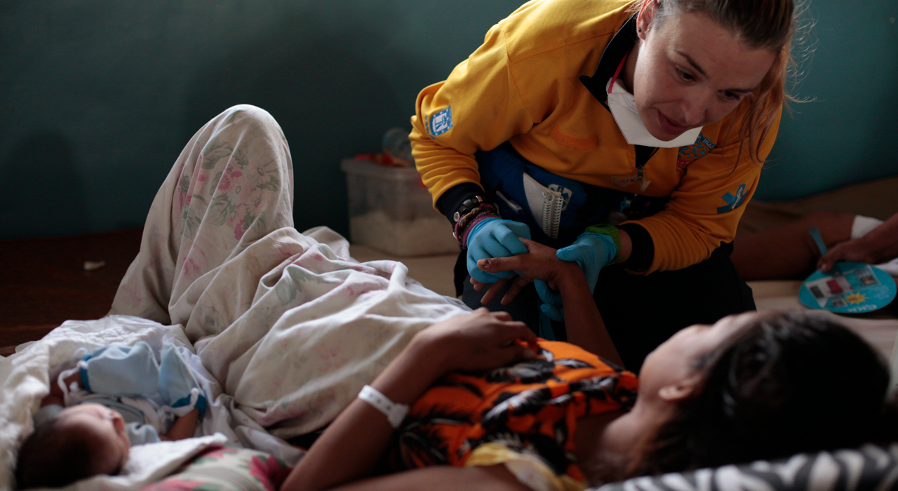 Une membre d’une équipe médicale d’urgence soigne une mère près de son nouveau-né lors de la réponse au typhon Haiyan, sur une photographie publiée par l’Organisation mondiale de la Santé.